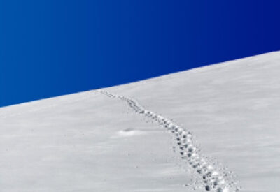 Footprints on a snowy hill with a blue sky