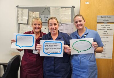 Staff holding speech bubble signs in relation to infection prevention control